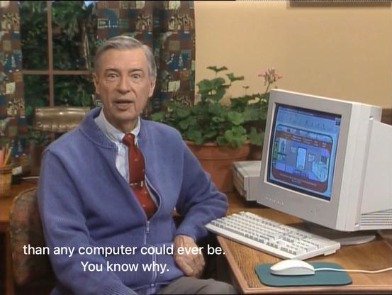 Screenshot of the Mister Roger's Neighborhood show. Mister Rogers sits in front of a mid-1990s-style PC, looking at the camera as he says, “than any computer could ever be. You know why.”