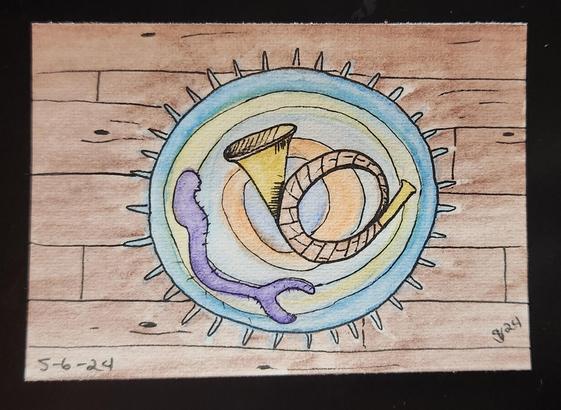 A post horn lying on a mermaid rug on a hardwood floor