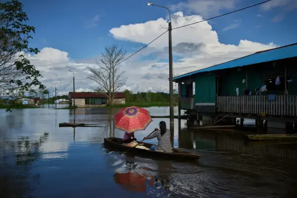 A mother and daughter in a canoe with a red umbrella.