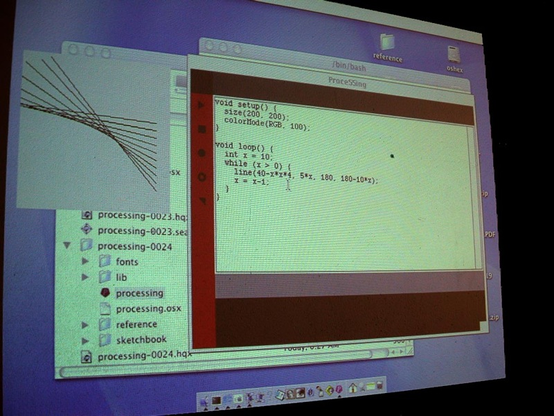 A photograph of an early version of the Processing (then styled as "Proce55ing") development environment running on a Mac desktop interface. The window displays a sketch with simple code using void setup() and void loop() functions, drawing a series of diagonal lines. Next to the editor is a small output window showing the visual result of the code. In the background, a Finder window is open, showing the directory contents of the "processing-0024" folder, including subfolders like "fonts", "lib", "reference" and "sketchbook." This image dates from April 2002 and captures an early stage in the development of Processing.
