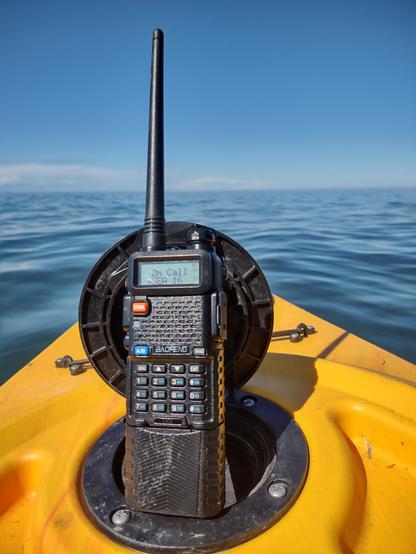 Picture of a 2m/70cm Baofeng UV-5R radio propped up in the drink holder of a kayak on Lake Ontario facing north