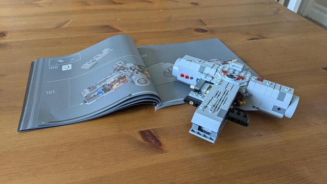 A partially assembled Lego Millennium Falcon (not the expensive one, unfortunately) next to the instruction manual.