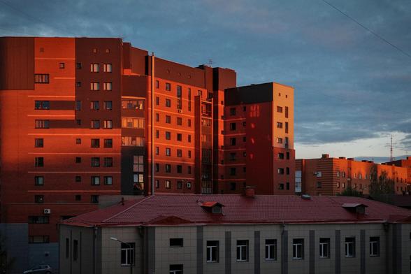 A multi-story brick building illuminated by the setting sun.