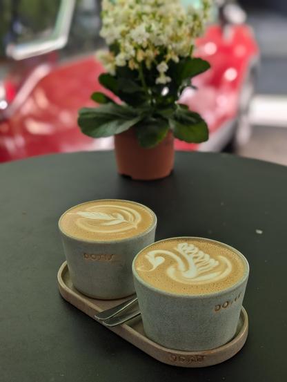 Two cups of coffe un a table with a flower. Very aesthetic photo