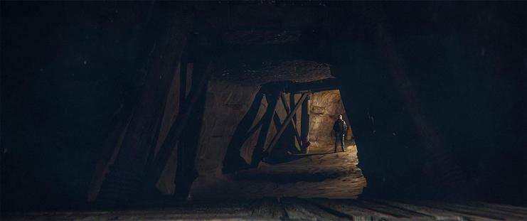 Wide shot, interior, day -

A tunnel with wooden structural supports in the mine. A man can be seen looking out from the tunnel, backlit by torchlight.