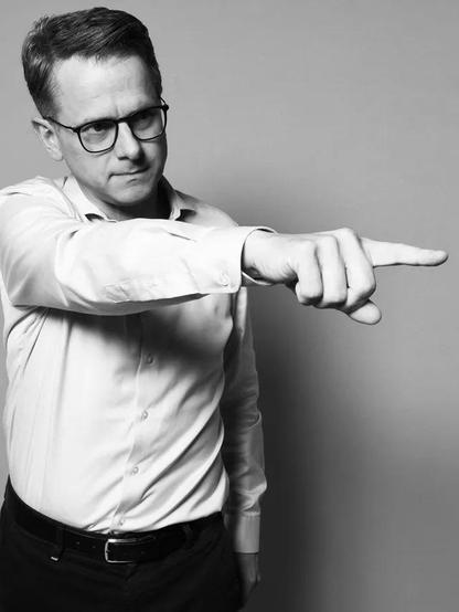 Carsten Linnemann streckt mit strengem Blick seinen gestreckten Arm mit spitzem Finger von sich weg.