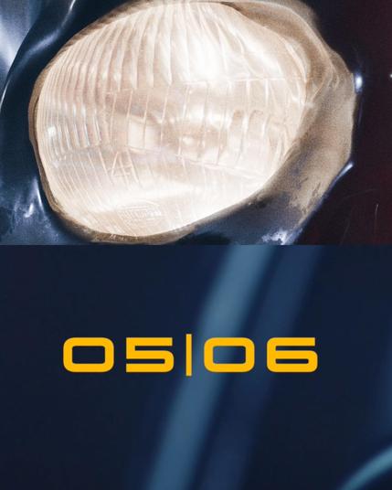 Das Bild besteht aus zwei Teilen. Oben ist ein detailliertes Bild eines Scheinwerfers, der von einem Fahrzeug ausgerichtet ist. Der Scheinwerfer hat eine transparente, rippige Oberfläche, die das Licht diffusiert. Die Umgebung des Scheinwerfers ist dunkel, was den Scheinwerfer hervorhebt. Im unteren Teil des Bildes befindet sich der Text "05|06" in einem auffälligen gelben Farbton auf einem dunkelblauen Hintergrund. Der Text ist klar und deutlich lesbar.
