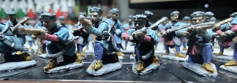 A close up of minis of kneeling infantry aiming down halfmuskets