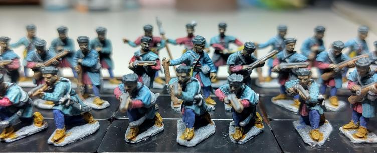 A wide shot of minis arranged in a 3 row formation, first row kneeling and aiming with halfmuskets