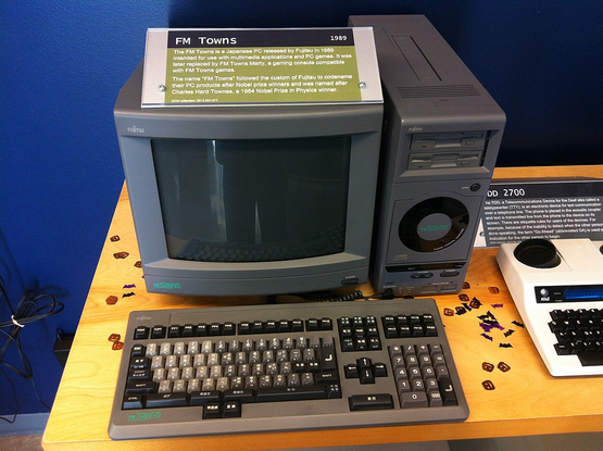 Photo of a 386DX-based Fujitsu FM Towns computer. It has a label on top of the CRT monitor that reads:

"The FM Towns is a japanese PC released by Fujitsu in 1989 intended for multimedia applications and computer games. It was later succeeded by the FM Towns Marty, a gaming console compatible with FM Towns games.

The name 'FM Towns' followed the custom of Fujitsu to codename PC products after Nobel Prize winners. This system was named after Charles Hard Townes, a 1964 Nobel Prize in Physics winner.

GCM collection: 2013.INV.877"