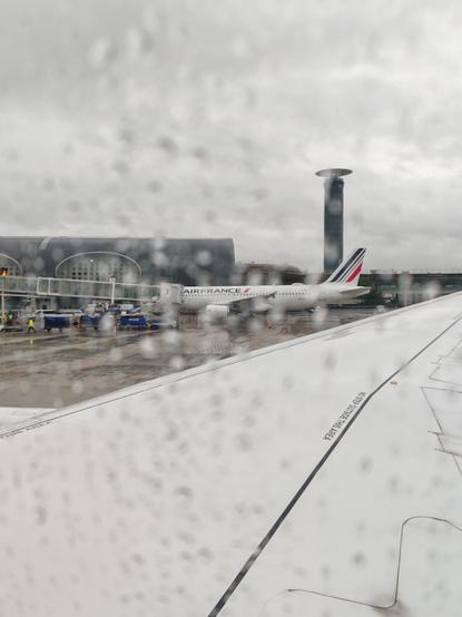 Photo blurry with the rain taken from the window of the plane. We see an Air France plane in front.