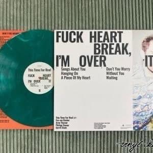Abgebildet ist eine Schallplatte mit einer grünen Scheibe und ihrem Cover. Auf dem Cover steht in fetter Schrift "FUCK HEART BREAK, I'M OVER" und es werden Songtitel wie "Songs About You", "Hang on", "A Piece Of My Heart" und andere aufgeführt.
