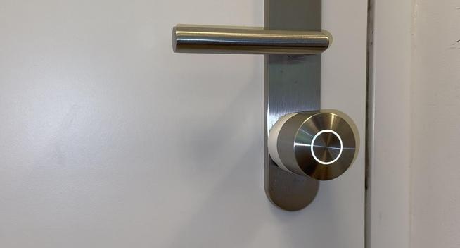 Zu sehen ist ein Nuki Smart Lock Pro (ein Intelligentes motobetriebenes und fernsteuerbares Türschloß das an der Innenseite einer Haus- oder Wohnungstüre angebracht wird und den Schlüssel dreht) der fünften Generation. 