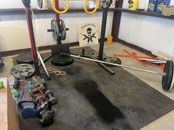 Landmine attachment with bar and weights, kettle bells and dumbbells on rubber mats