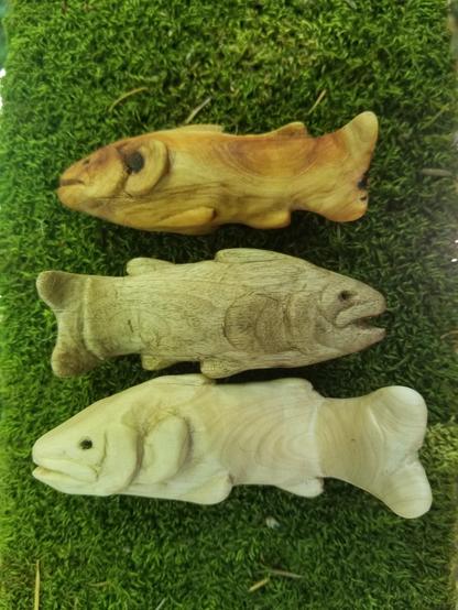 three carved trout, each in a different type of wood: rosy redwood, silvery myrtlewood, pale maple