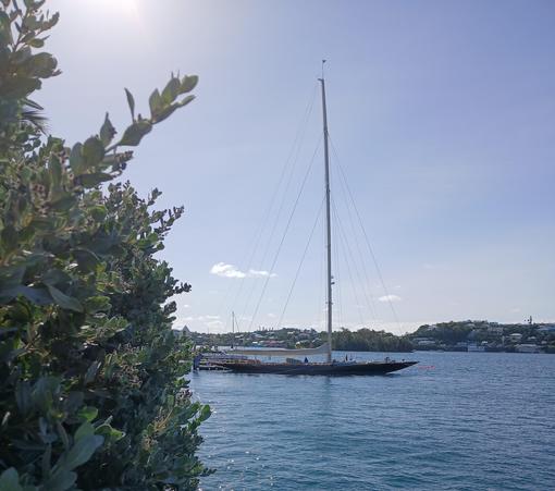 Distant view of dark blue very large traditional sloop, J-Class yacht Velsheda, moored on a sunny day.