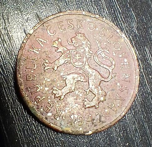 Tails of a coin, with the state symbol in the middle - a lion with two tails and a crown, representing the Czech republic, with the Slovak double cross on a mountain peak on its chest. Around the edge there is the year 1947 and the name of the state - Republika Československá. 