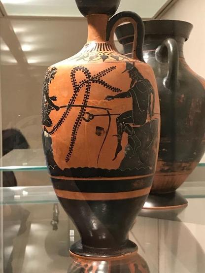 The immortals of Mount Olympos were not exclusively engaged in momentous feats. In this black-figure vase painting, three of them are shown fishing, each perched on a rock. Poseidon (not shown) holds his catch in one hand, his trident in the other. Herakles tries his luck with a rod while Hermes gesticulates at him, probably talking rather than fishing. He wears his boots, traveller's hat, and short chlamys cloak. His kerykeion staff rests in his right hand.
