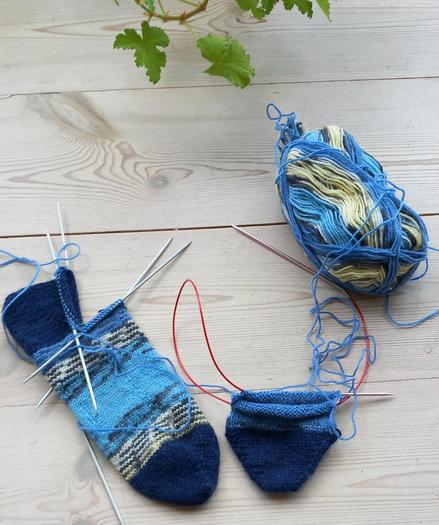 Chausettes en tricot en cours de tricotage, pointes et talons bleu marine, reste bleu clair, blanc, gris