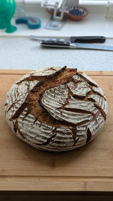 Brot auf einem Holzbrett im Hintergrund liegt ein Messer