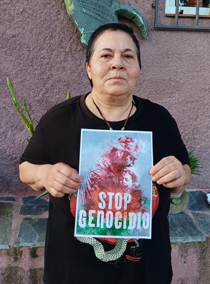Una mujer sosteniendo un cartel con el lema STOP GENOCIDIO.