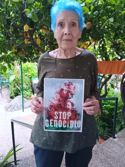 Una mujer sosteniendo un cartel con el lema STOP GENOCIDIO.