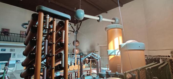 im Blick in das Hochspannungsprüffeld mit Spulen und anderen elektrotechnischen Komponenten.