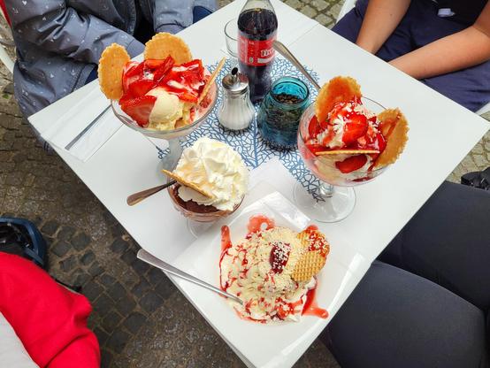 Four bowls with ice cream and a coke on a table
