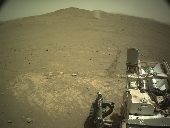 An ochre toned image of the plains west of the rim of Jezero Crater captured by the Perseverance rover from the Krokodillen plateau. This picture records a dust devil twisting through the landscape in the distance, with the tracks of the rover in the foreground.
May 29, 2025 (Sol 1519). 
Credit images: NASA/JPL-Caltech