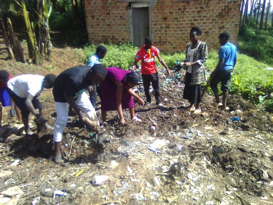 Young farmers picking out plastic bottles and polythene papers from the soil