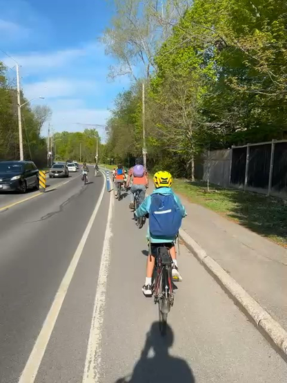 Un vélo-bus circule en file sur une piste cyclable. Bike bus rolling down single file in a painted bike lane