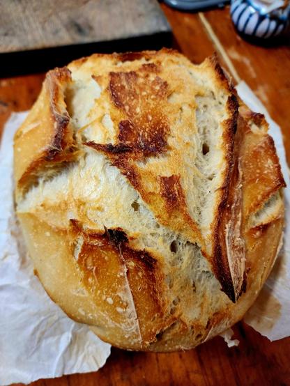 A boule loaf of bread with deep tan crust and open scoring.