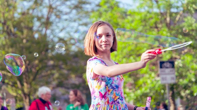 Girl in butterfly dress and bob haircut blows bubbles with a large and