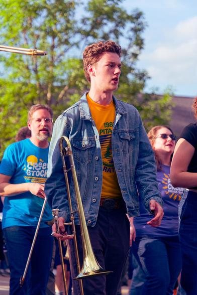 Man holds brass instrument in parade group looks to the left