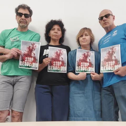 Dos hombres y dos mujeres sosteniendo carteles con el texto STOP GENOCIDIO.