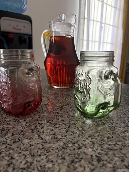 A pitcher of iced tea and two Mason jar glasses. 