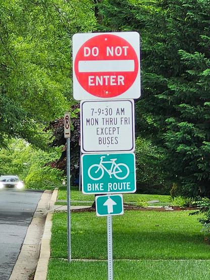 Bike route sign on same pole with signs saying Do Not Enter 7-9:30 am