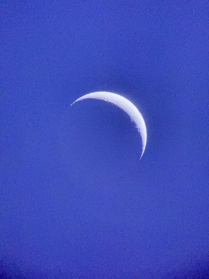 A crescent moon against the blue sky