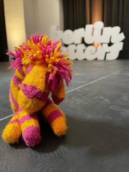 Yellow and pink knitted zebra with berlin letters logo in background