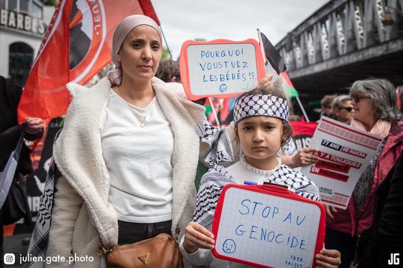À quelques pas de la station de métro Barbès-Rochechouart, une manifestante brandit une ardoise sur laquelle on peut lire : « Pourquoi vous tuez les bébés !? ». À ses côtés, une enfant en tient une autre, portant le message : « Stop au génocide. Free Palestine ». À l’arrière-plan, une pancarte proclame : « 77 ans de Nakba, il y a toujours urgence en Palestine ».