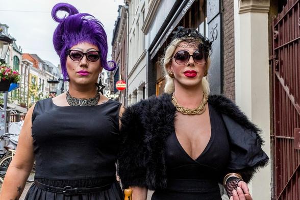 #AltTextForYou
 kleurenfoto van twee #crossdressers in een oude binnenstad van Utrecht. Ze lopen naast elkaar, maar dat kan je niet zien want hun benen staan er niet op. Ze hebben een vastberaden uitdrukking, hun lippen zijn gestift en ze zijn in het zwart gekleed. De linker heeft een paarse hoge coiffure en de rechter is blond en heeft een diep decolleté. Ze dragen allebei een zonnebril, die hun blik iietwat verbergt.


Vertalen
