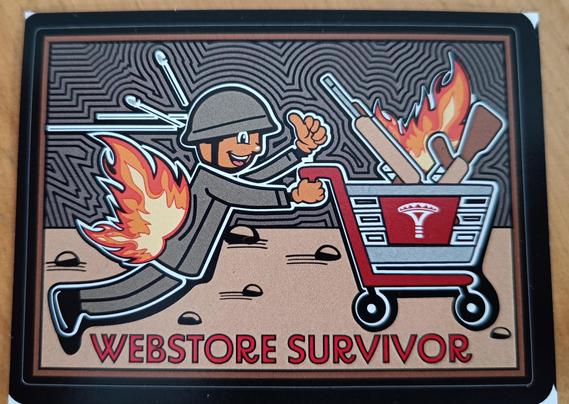 Tarra, jonka kuvassa vihreään asuun ja kypärään pukeutunut asiakas työntää Varustelekan ostoskärryä tulen alla.
Tarrassa teksti: "Webstore survivor"