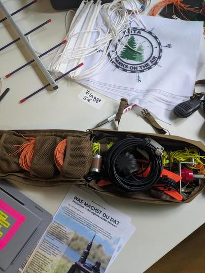 Tasche mit Antennen Equipment, im Hintergrund liegen weiße Flaggen mit den POTA Logo (grüne Bäume in einem stilisierten Kompass)