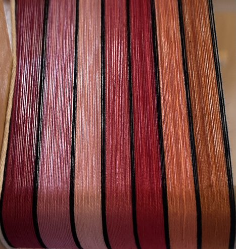 7 colours of warp threads in pink, red and orange shades with black threads between each colour