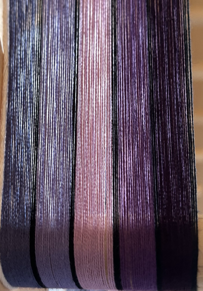5 colours of warp threads in lilacs and purples with black threads in between each colour 