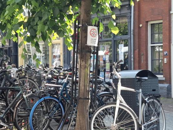 Many bicycles parked behind a sign saying 'Do not park bicycles here'