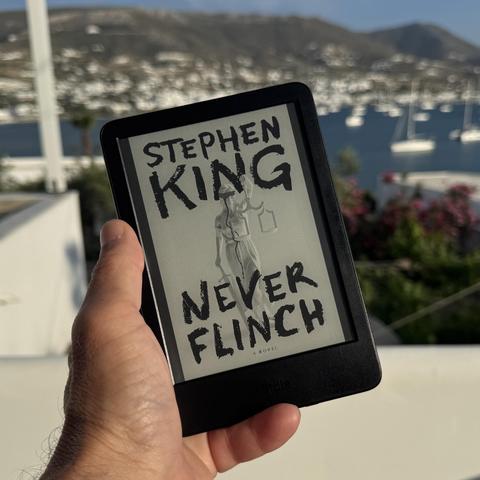 Never Flinch, Stephen King’s latest novel cover on my Kindle, with Parikia bay as a backdrop