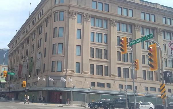 Colour photo of the former Hudson's Bay Company Building in downtown Winnipeg, looking southeast from the corner of Portage Avenue and Memorial Boulevard.
The building is six storeys and has a slight Art Deco style to it.
