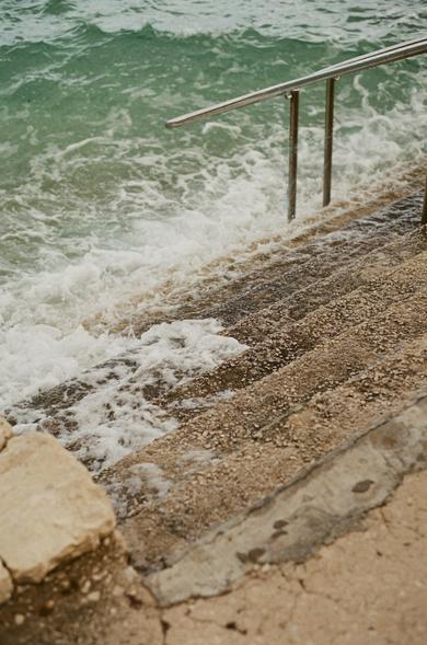 Stone stairs leading down to turquoise water foaming at the bottom.
