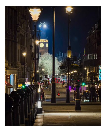 A nighttime shot down Whitehall in London, taken from Trafalgar Square towards Parliament. A very bright set of lights are hoisted high above, leaving the trees outside the Ministry of Defence oddly lit in the darkness, whilst behind them looms the Elizabeth Tower in its newly-refurbished finery. 